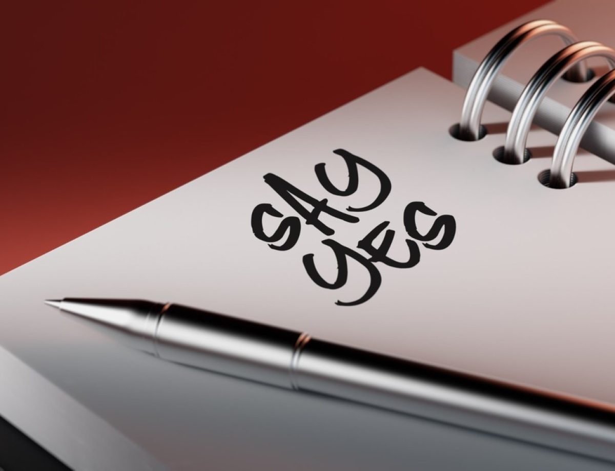 An Open Dairy on a Desk With The Word Say Yes Written on One of The Pages
